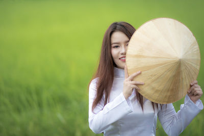 Portrait of beautiful woman holding hat at farm
