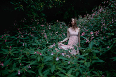 Woman in beautiful dress standing in between pink flowers