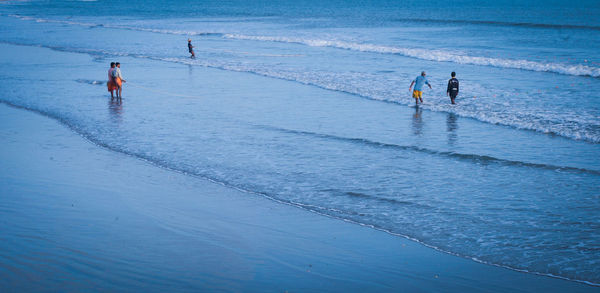 People fishing on beach at dusk