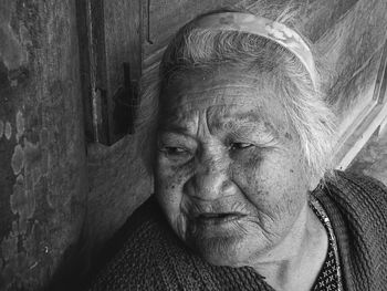 Close-up of senior woman looking away while sitting against door at home
