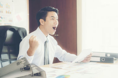 Happy businessman screaming at desk in office