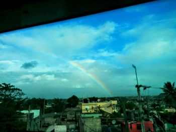 Rainbow over city against cloudy sky