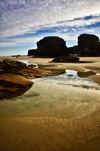 Rocks on beach against sky during sunset