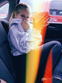 Side view portrait of young woman sitting in car