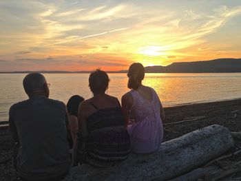 Rear view of people looking at sea during sunset