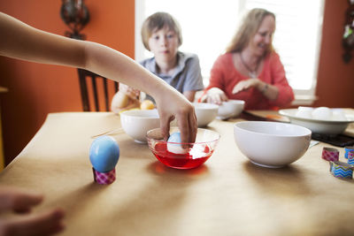 Cropped image of girl decorating easter eggs with family at home