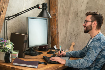 Side view of man using laptop while sitting on table