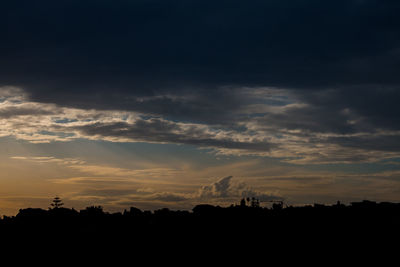 Silhouette landscape against dramatic sky during sunset