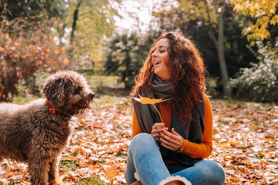 Young woman with dog sitting in park