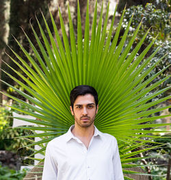 Portrait of young man standing against plants