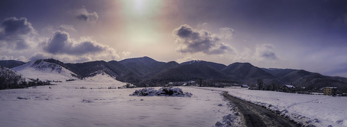 Panoramic view of snow covered mountains against sky