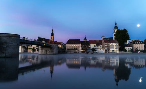 Reflection of buildings in lake against sky at night