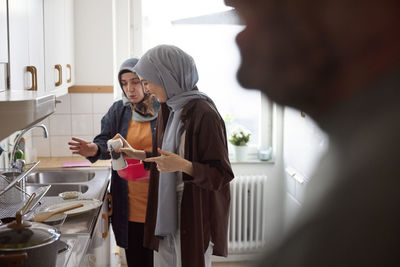 Women in headscarves cooking together for eid al-fitr at home