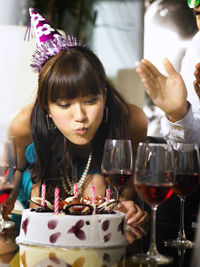 Close-up of young woman blowing candles on birthday cake