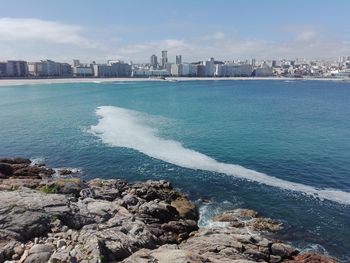 Scenic view of sea by buildings against sky