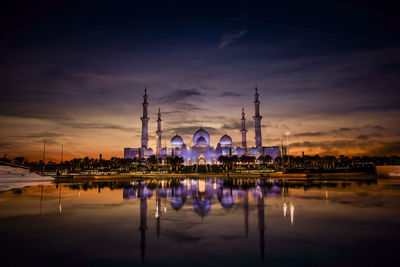 Reflection of illuminated buildings in water at sunset