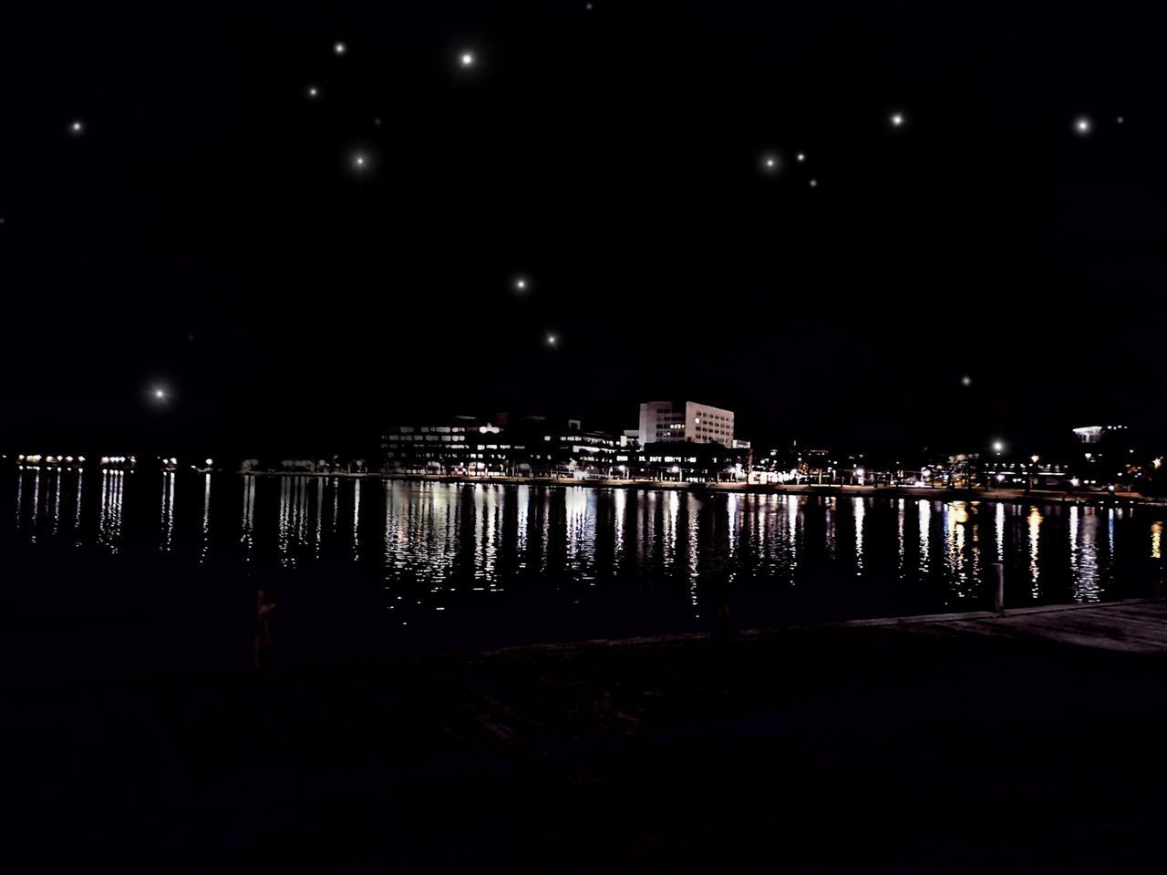 ILLUMINATED BUILDINGS BY RIVER AGAINST SKY