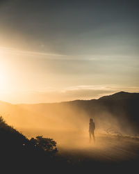 Silhouette man standing on mountain against sky during sunset