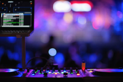 Close-up of sound mixer against illuminated defocused lights at night
