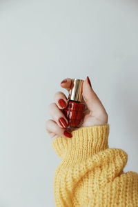 Close-up of hand holding glass over white background