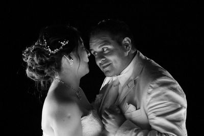 Newlywed couple dancing against black background