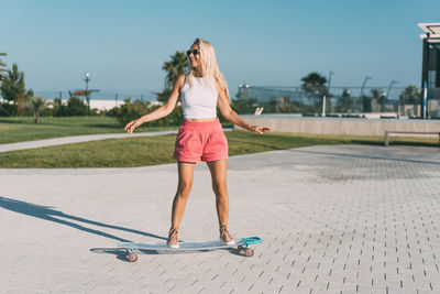 Beautiful stylish woman surf on a longboard on a hot summer day. summer hobbies and sports.