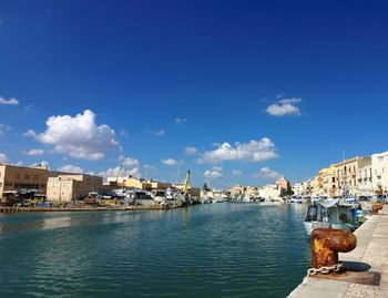 View of buildings at waterfront against blue sky
