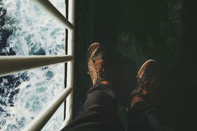 Low section of woman standing by railing over sea