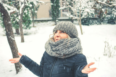 A woman standing in the backyard while snowing