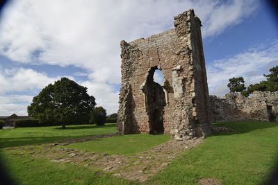 Old ruin building on field against cloudy sky