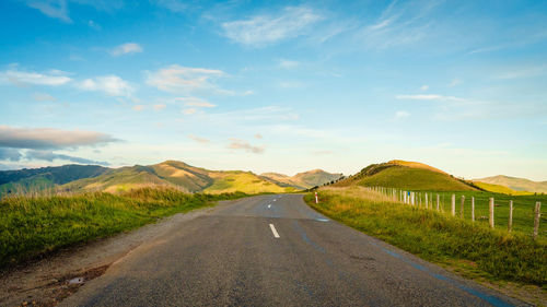 Road leading towards mountains against sky