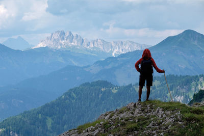 Rear view of man standing on mountain against sky