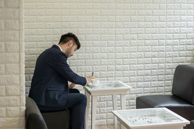 Businessman having coffee while sitting at table in office