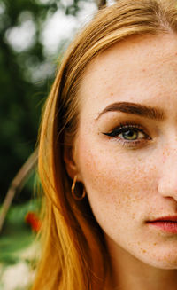 Close-up face of a young ginger freckled woman with red hair and perfect healthy freckled skin