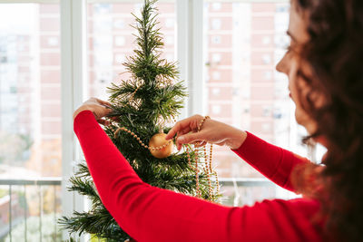 Close-up of woman decorating christmas tree at home