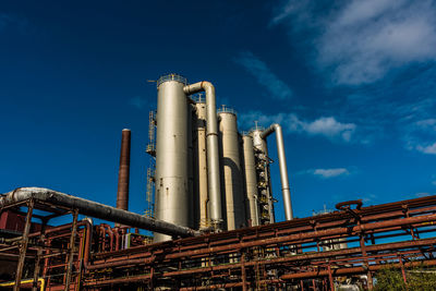 Low angle view of industry against blue sky