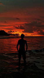 Silhouette man standing on beach against sky during sunset