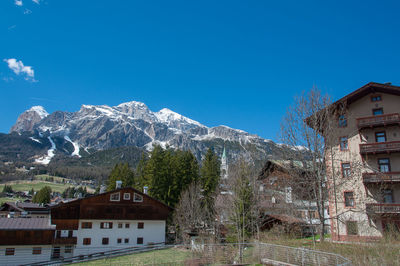 Buildings by mountain against blue sky