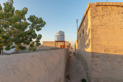 Footpath by building against clear sky