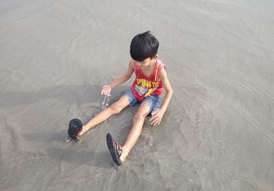 High angle view of boy jumping on sand at beach