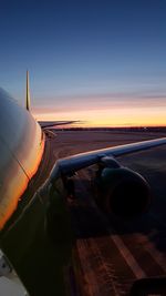 Airplane on runway against sky during sunset