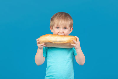 Portrait of boy holding ice cream against blue background
