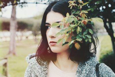 Portrait of beautiful young woman against plants