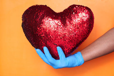 Close-up of hand holding heart shape over white background