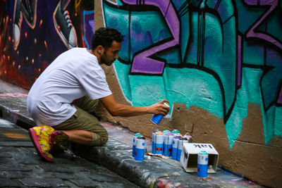 Side view of a young man painting on wall