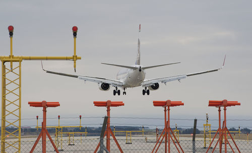 Airplane flying over airport runway against sky