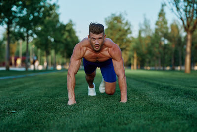 Portrait of shirtless man exercising on field