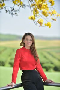 Portrait of smiling young woman standing against trees