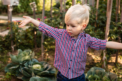 Boy with arms raised standing against plants