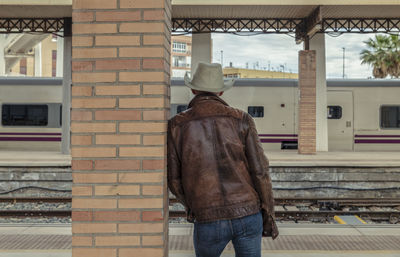 Rear view of adult man on cowboy hat waiting in train station. almeria, spain